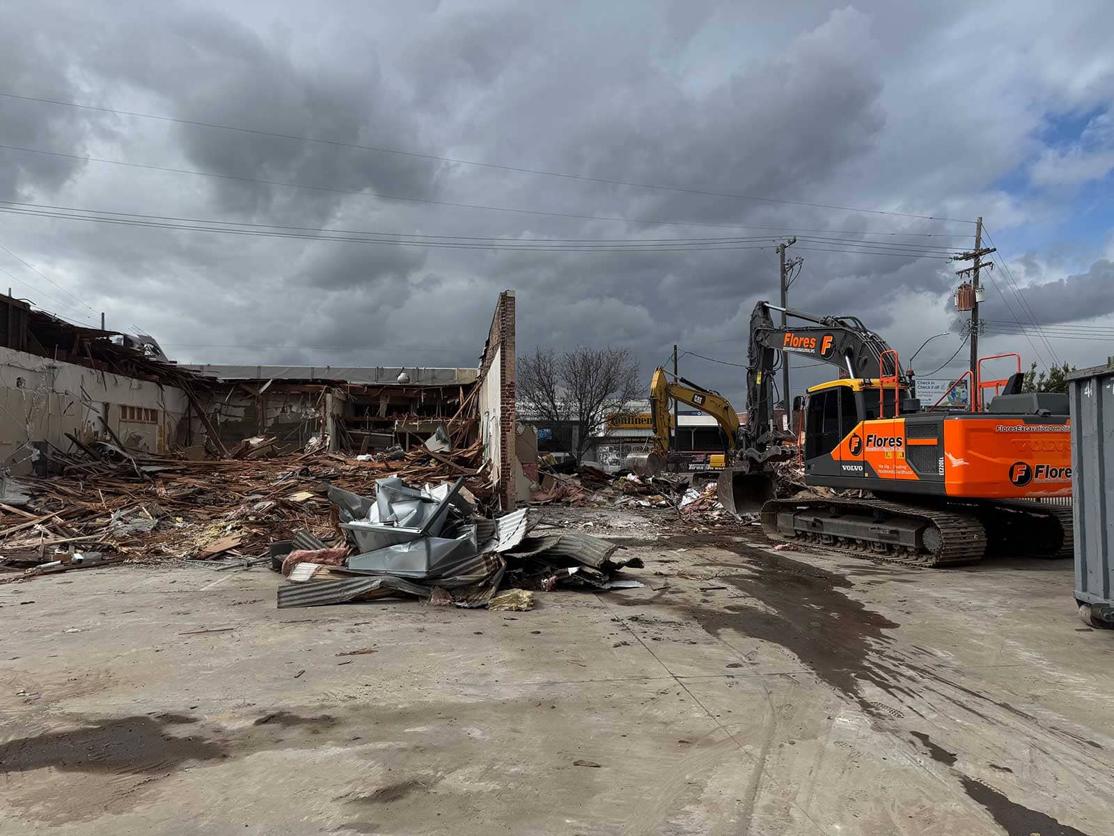 Flores excavator working beside a demolished structure